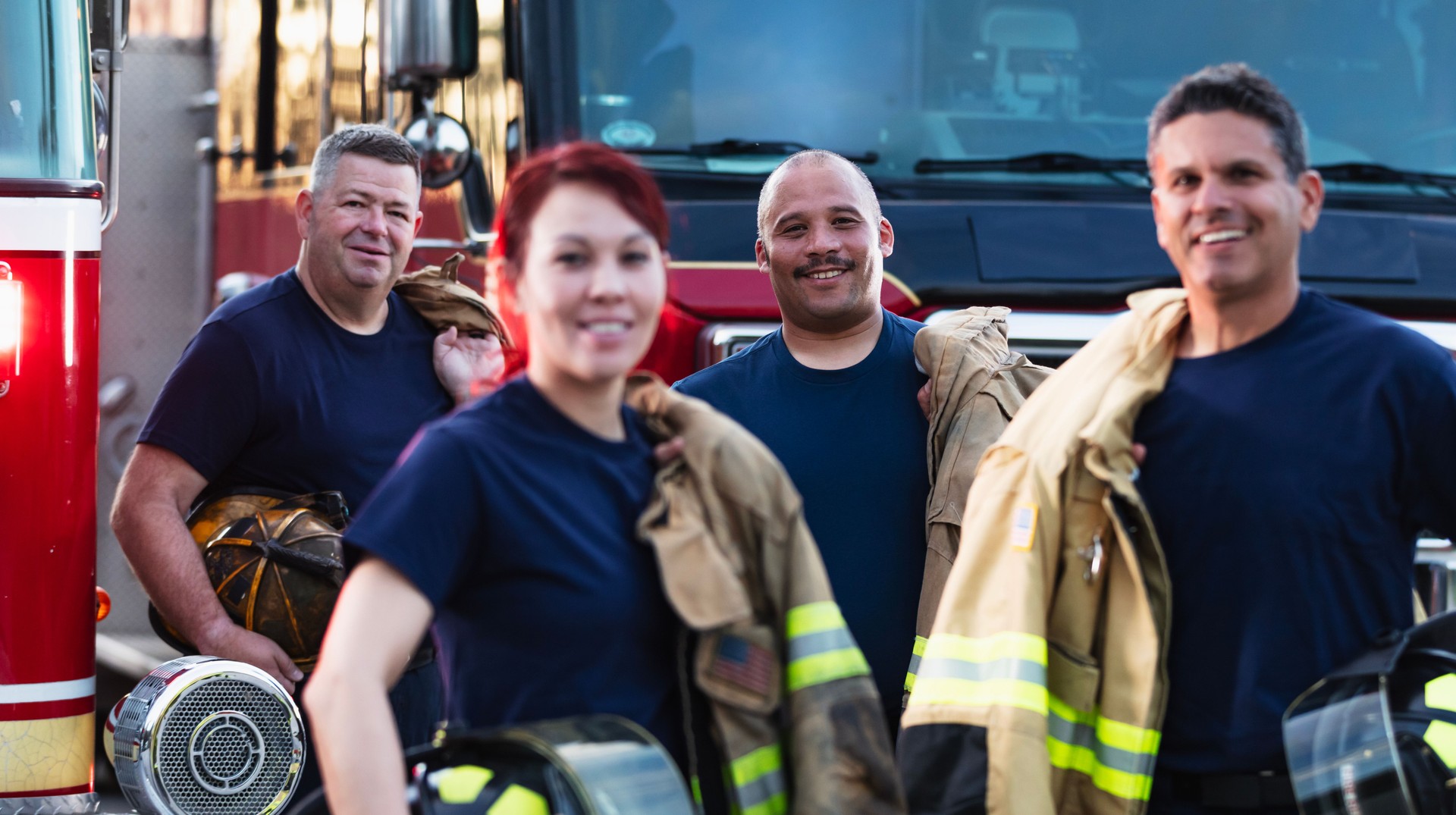 Multiracial group of four firefighters smiling at camera